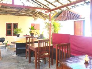 a dining room with tables and chairs and a red wall at saha surf camp in Arugam Bay