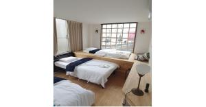 a room with three beds and a window at Nagoya Hostel The Three Smiles / Vacation STAY 13462 in Nagoya