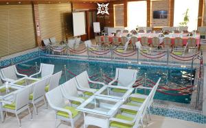 a swimming pool with white chairs and a table and a table at Kabul Star Hotel & Restaurant in Shīrpūr