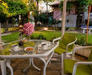 a table with cups and a vase with flowers on it at Garden House Katerini in Katerini