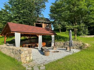 a pavilion with a picnic table and a stone wall at Kousek ráje in Třinec