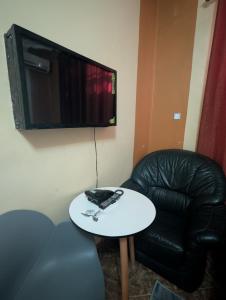 a black leather chair and a table and a television at New Africa one inn in Dar es Salaam