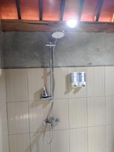 a shower in a bathroom with a light on the wall at Aura V Bungalow in Praya