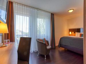 a hotel room with a bed and a chair and a desk at Stuttgart Großbettlingen Hotel by Belvilla in Großbettlingen