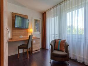 a hotel room with a desk and a chair and a television at Stuttgart Großbettlingen Hotel by Belvilla in Großbettlingen