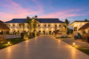 a large white building with lights in front of it at White House Hotel Kamphaeng Phet in Ban Tha Dua