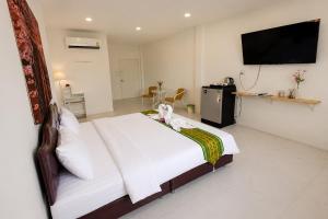 a bedroom with a white bed and a flat screen tv at White House Hotel Kamphaeng Phet in Ban Tha Dua