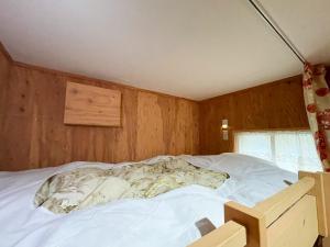 an unmade bed in a room with wooden walls at Guesthouse Otaru Wanokaze women's domitory / Vacation STAY 32191 in Otaru
