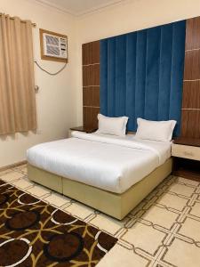 a bedroom with a large bed with a blue headboard at كيان الين الشبلان - KAYAN ALYN AlMansak Suites in Abha