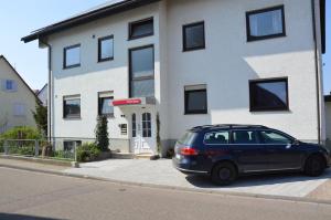 a blue car parked in front of a white building at Ferienwohnung Diana in Rust