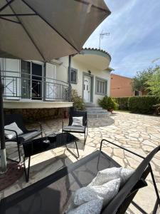 a patio with chairs and an umbrella in front of a house at VILLA ERMIONI in Melíkia +3 photos