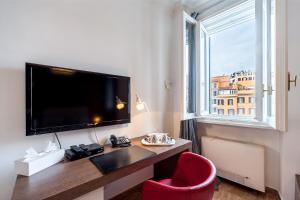 Cette chambre comprend un bureau avec une télévision et une chaise rouge. dans l'établissement La Dolce Vita Barberini, à Rome