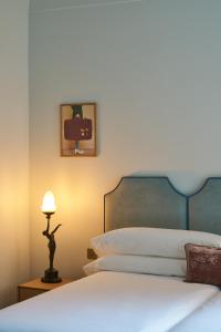 ein Schlafzimmer mit einem Bett mit blauem Kopfteil und einer Lampe in der Unterkunft Le Berger Latroupe Hotel in Brüssel