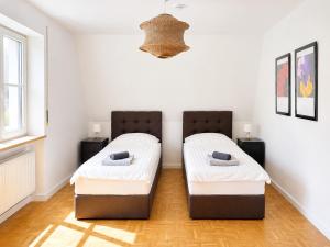 two beds in a room with white walls at SCHEE Panorama Apartment - ideal für Gruppen und Familien in Nördlingen