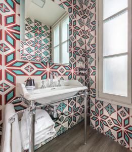 a bathroom with a sink and a mosaic wall at Hotel L’Antoine in Paris