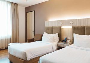 a hotel room with two beds and a desk at Hotel Wisata Niaga in Purwokerto