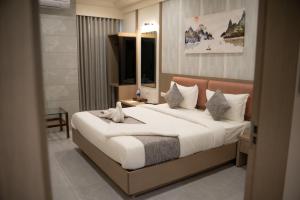a bedroom with a large bed with white sheets at Hotel Emirest in Bhilad +21 photos