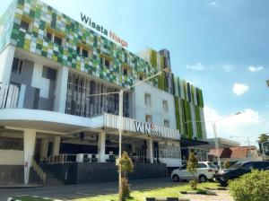 a building with cars parked in front of it at Hotel Wisata Niaga in Purwokerto