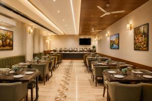 a dining room with tables and chairs and a flat screen tv at Hotel Luxury Inn Delhi Airport in New Delhi