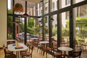 ein Restaurant mit Tischen und Stühlen und großen Fenstern in der Unterkunft Le Berger Latroupe Hotel in Brüssel