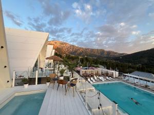 a hotel with a pool and chairs and a mountain at Balandda Chimgan in Chimgan