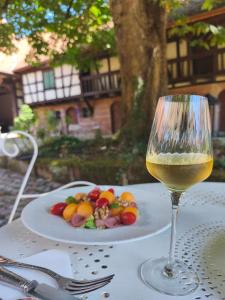 a glass of wine sitting on a table with a plate of food at Au Fil du Temps in Imbsheim