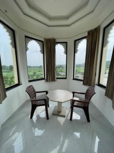 a room with a table and two chairs and windows at Marudhar Resort in Chittaurgarh