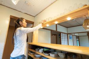 a woman is reaching for a shelf in a room at Hide A Way - Vacation STAY 90104v in Nishinoomote