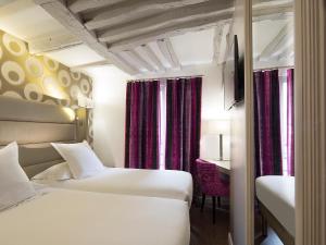 a hotel room with two beds and a desk at Hôtel Jacques de Molay - Fitness & Sauna in Paris