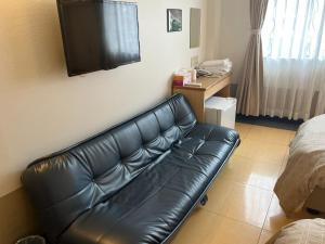 a black leather couch in a room with a television at Hotel Yamadaso - Vacation STAY 41334v in Nago