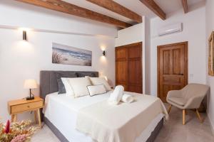 a white bedroom with a bed and a chair at Can Perla in Sóller