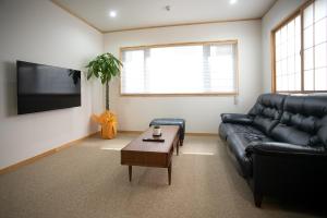 a living room with a black leather couch and a coffee table at Nagi - Vacation STAY 55367v in Katori