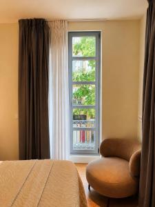 a bedroom with a bed and a chair and a window at Legazpi Doce Rooms & Suites in San Sebastián