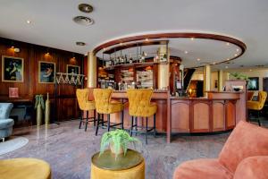 a bar in a restaurant with yellow bar stools at Hotel Tongerlo in Roosendaal