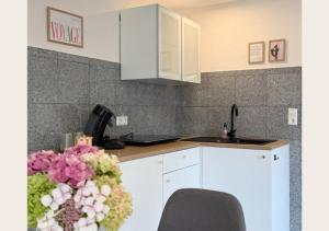a kitchen with white cabinets and a vase of flowers at hortensiengarten in Teningen