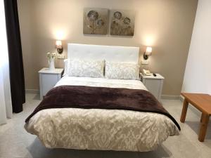 a bedroom with a large white bed with two tables at Hostal Alcázar in Toledo