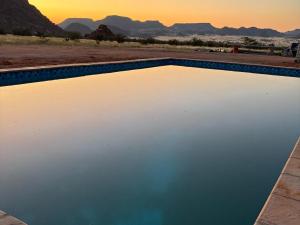 a pool of water with the desert in the background at Sky and Stone Tented Camps in Twyfelfontein