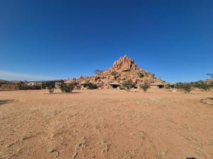 a desert field with a mountain in the background at Sky and Stone Tented Camps in Twyfelfontein