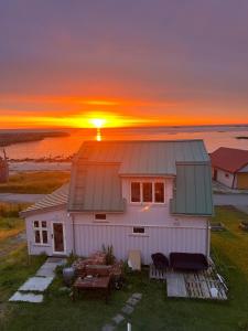 a house with the sunset in the background at NEW house by the beach in Andøya