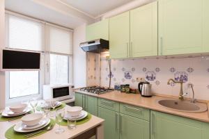 モスクワにあるLux Apartments -MoscowCitiのキッチン(緑のキャビネット、ワイングラス付きのテーブル付)