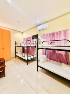 two bunk beds in a room with pink curtains at Casa Ysabel Transient Inn in Ayusan Norte