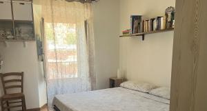 a bedroom with a bed and a window and a chair at Bilocale con terrazzo in centro storico in Dorgali