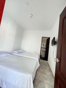 two beds in a white room with a mirror at Hospedaje Dora in Máncora
