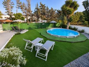 a yard with two chairs and a swimming pool at Cavo Prima Kiotari in Gennadi