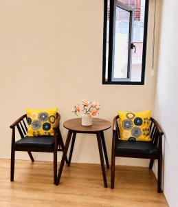 two chairs and a table with a vase of flowers at Hue Ancient Hostel in Hue