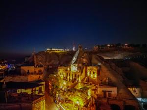 a building with a clock on the side of a hill at night at Ascension Cave Suites - Special Class in Göreme