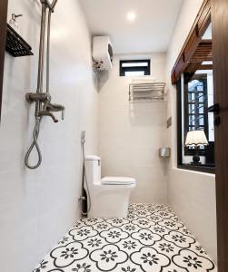 a bathroom with a toilet and a black and white tile floor at Hue Ancient Hostel in Hue
