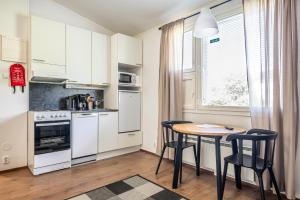a kitchen with white cabinets and a table and chairs at LODGE Hostel Kuusamo in Kuusamo