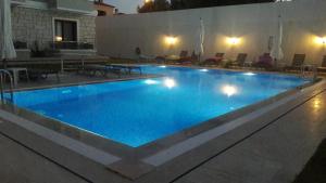 a large swimming pool with blue water at night at Süreyya Hanım Otel in İzmir +6 photos