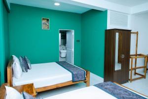 a room with two beds and a green wall at JAI REST In in Jaffna